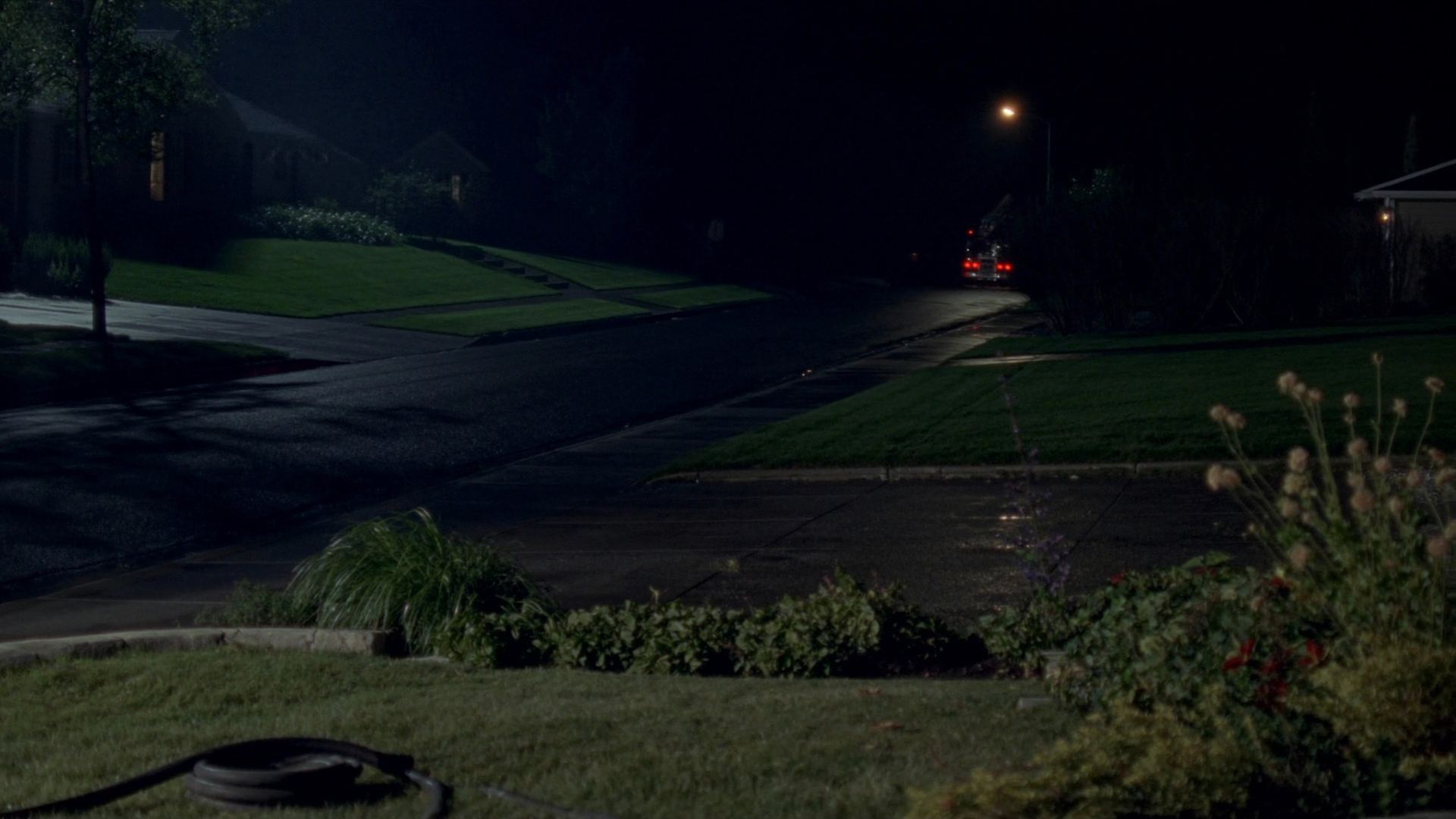 An empty wet street at two in the morning, tail lights leaving in the distance.