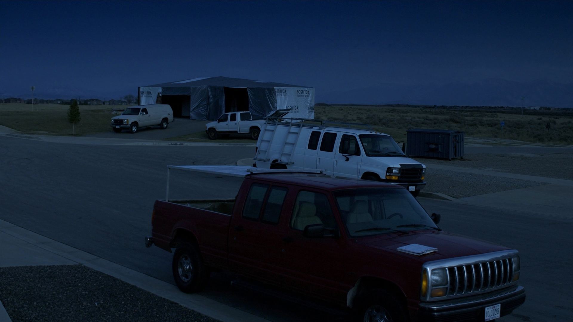 Work trucks parked along a residential curb in the early morning.